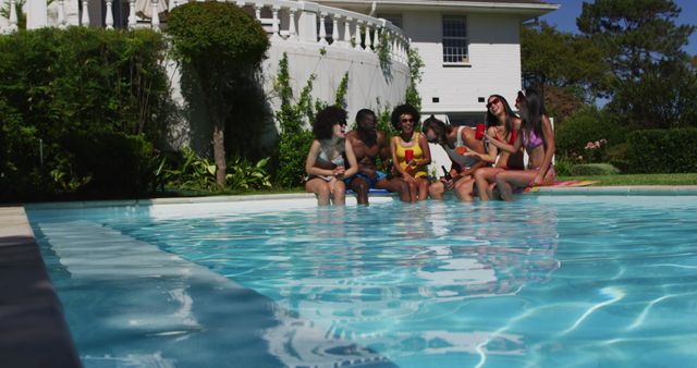 Group of friends sitting at edge of pool, laughing and enjoying each other's company on sunny day. Ideal for use in summer vacation promotions, advertisements for swimwear or outdoor leisure activities, and social bonding or friendship themes.