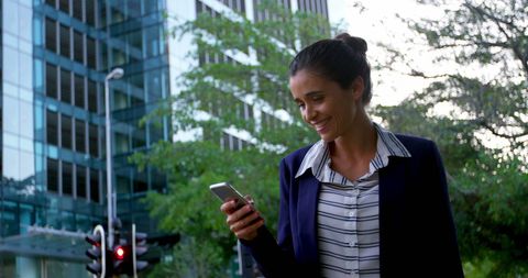 Happy Businesswoman Checking Her Smartphone Outdoors
