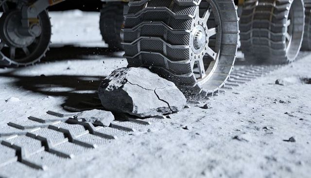 Rover wheel crushing cracked rock on lunar regolith with detailed tread and bolted rim