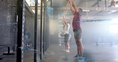 Athletes Exercising with Technology Assistance in Modern Gym