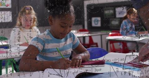 Young student writing in workbook during classroom math lesson, concentrating on assignment