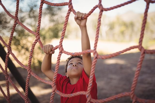 Determined boy climbing a net during obstacle course in boot camp