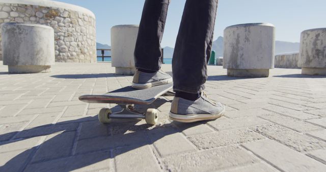 Features close-up of person's legs while balancing on skateboard in bright urban setting. Ideal for lifestyle, urban culture, streetwear, youth recreation, and sport-related themes in advertisements, blogs, and social media posts.