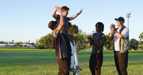 Celebrating victory: diverse cricket team lifting teammate, cheering and high-fiving
