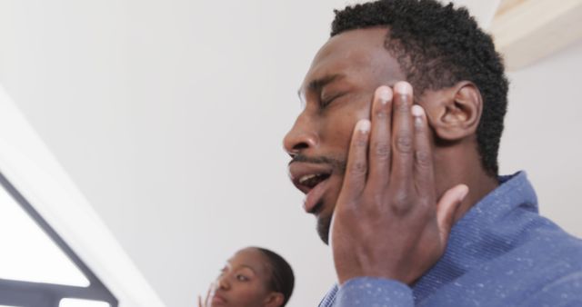 Tired African American Man Rubbing Face with Coworker in Background - Download Free Stock Images Pikwizard.com