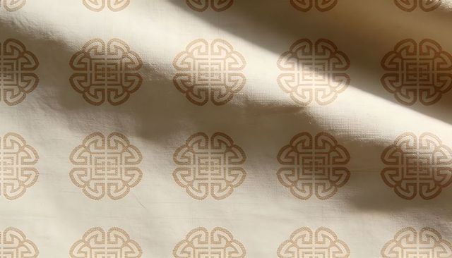 Light cream fabric with decorative knot motif pattern, woven texture and gentle shadow