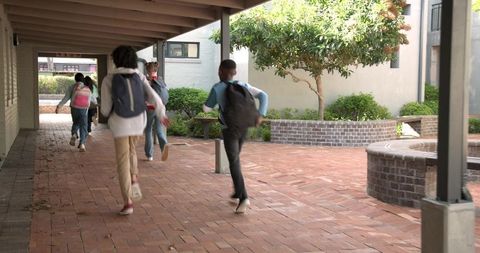 Children Walking Along Brick School Walkway with Backpacks