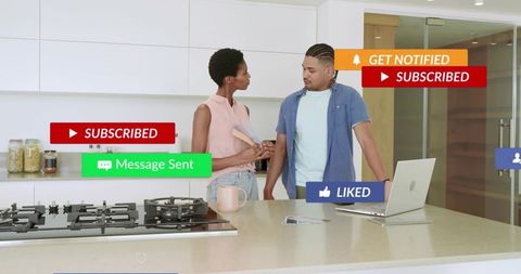 Friends discussing kitchen design at island holding color samples and laptop for renovation planning