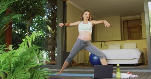 Pregnant Woman Practicing Yoga with Online Lessons in Tranquil Home Environment