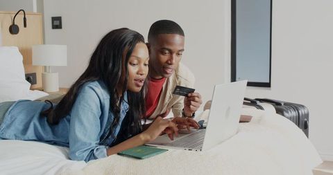 Couple Booking Travel Online Lying on Cozy Hotel Bed