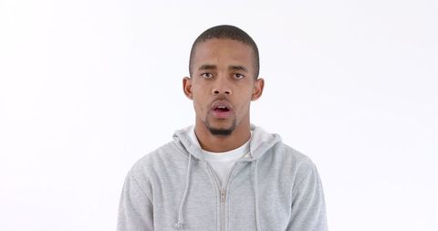 Surprised Young Man in Gray Hoodie Posing Against Plain Background