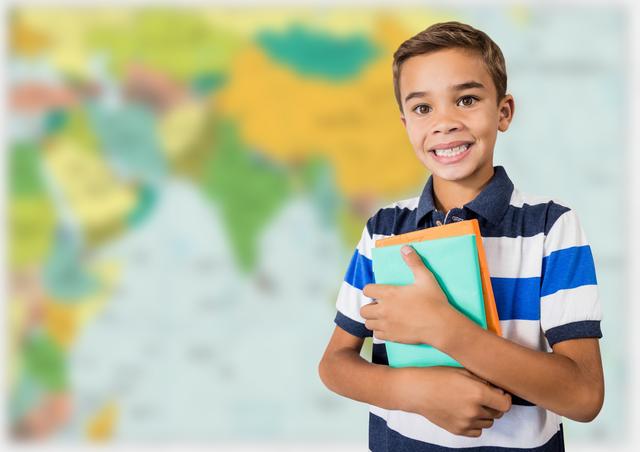 Smiling boy holding books with blurry map background good for educational websites, school advertisements, or learning resource materials. Suitable for promotional content on geography or global education initiatives.