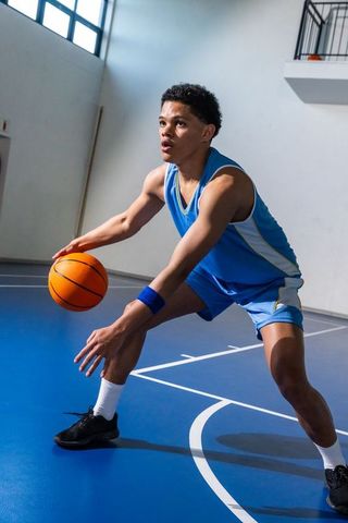 Teenage athlete dribbling basketball on indoor court