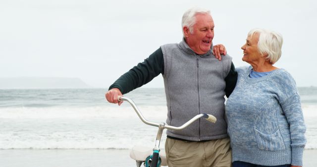 Senior couple joyfully walking on the beach, embracing and sharing moments of happiness. Ideal for illustrating concepts related to retirement, joyful living, wellbeing in old age, outdoor activities for seniors, and loving relationships in later years.