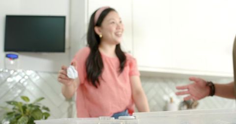 Kitchen organizing with clear plastic storage bins and smiling woman handing item