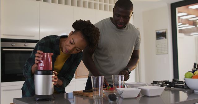 Image of happy african american couple preparing juice in kitchen. Love, relationship and spending quality time together concept.