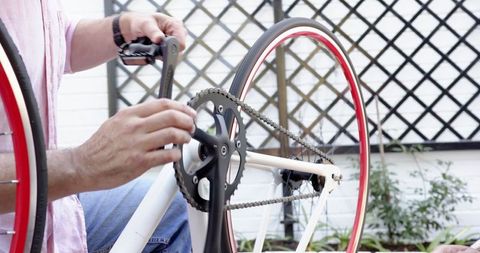 Man Repairing Bicycle Pedal on Outdoor Patio
