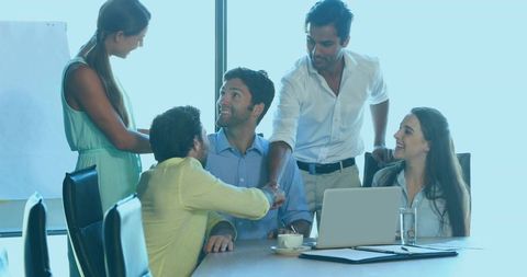 Business team shaking hands closing meeting in modern boardroom with laptop