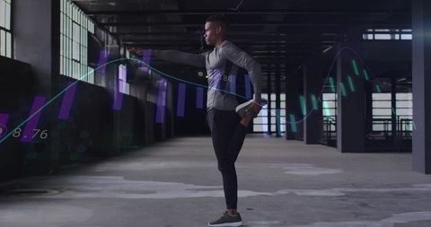 Athlete stretching and balancing in industrial warehouse with futuristic data overlays