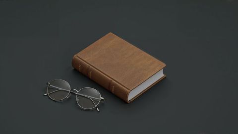 Vintage leather-bound book and classic eyeglasses on dark gray surface