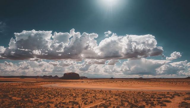Sunlit Desert Track Curving Toward Monumental Buttes Beneath Dramatic Cumulus Sky
