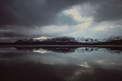 Dramatic Mountain Range Reflection in Calm Water at Dusk