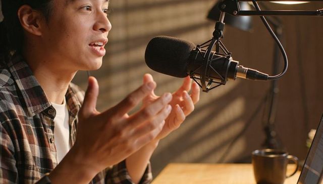 Content creator speaking into professional microphone for podcast recording at home studio