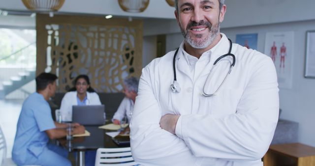 Confident Doctor Smiling in Hospital, Medical Team Meeting in Background - Download Free Stock Images Pikwizard.com