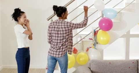 Two Women Decorating Staircase with Balloons for Celebration