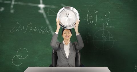 Caucasian Female Teacher Holding Clock Overhead Classroom