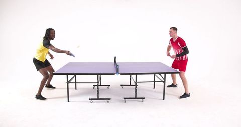 Diverse Men Engaging in Dynamic Table Tennis Match Indoors