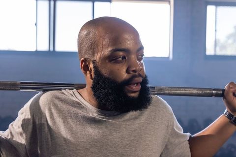 African american man lifting barbell, sweating and focusing in gym workout