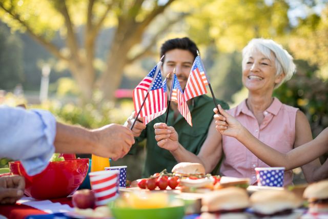 Family holding american flags while having meal in the park - Download Free Stock Photos Pikwizard.com
