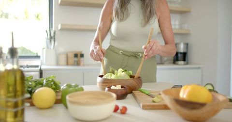 Mature Woman Making Fresh Salad in Modern Kitchen Setting