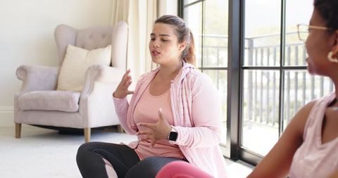 Woman leading wellness conversation during home yoga session in sunlit living room