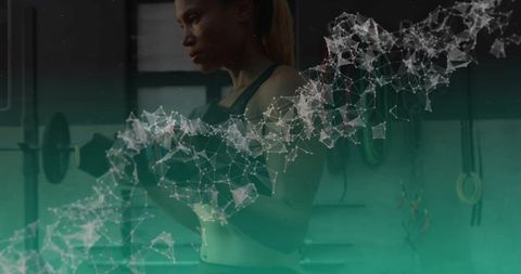 Focused woman lifting dumbbell in gym with teal particle network overlay for fitness tech