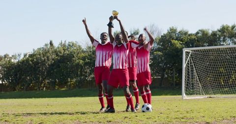 Youth soccer team celebrating victory with trophy on sunny field