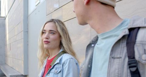 Young friends walking and talking along urban sidewalk in daylight, street conversation