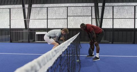 Diverse Tennis Players Looking at Ball on Court Net Mid-Game