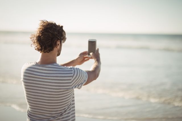 Man Taking Photo of Sea on Sunny Beach Day - Download Free Stock Images Pikwizard.com