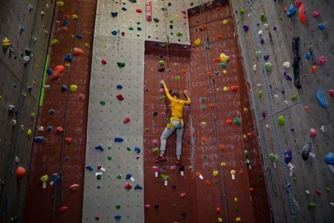 Female Climber Scaling Indoor Wall in Vibrant Colorful Gym