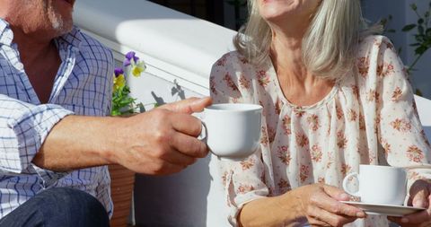 Senior couple enjoying coffee together outdoors in sunny setting