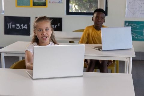Diverse students using laptops in classroom learning math and digital skills