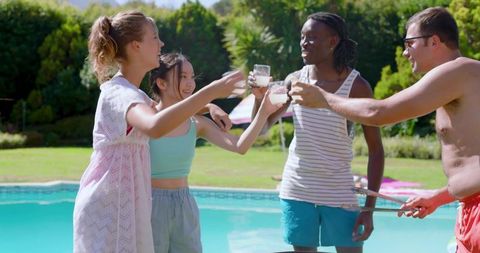 Diverse group of friends enjoying poolside celebration with drinks