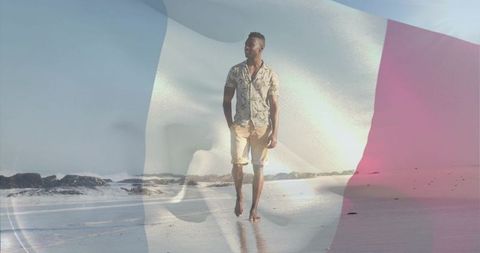 Walking man on tranquil beach with subtle tricolor flag overlay