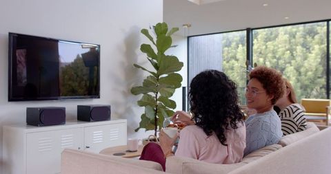Diverse Female Companions Enjoying Home Relaxation in Modern Living Room
