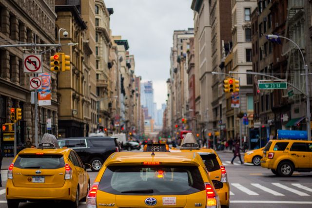 Photo captures bustling city street filled with yellow taxis and surrounded by historic buildings. Ideal for conveying themes of urban life, metropolitan transportation, busy city scenes, or travel experiences.