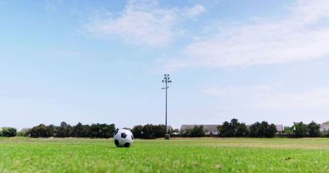 Soccer Ball on Lush Green Suburban Field with Clear Sky