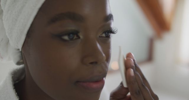 Portrait of african american attractive woman removing make up in bathroom. beauty, pampering, home spa and wellbeing concept.