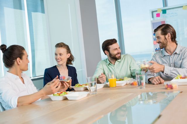 Smiling business executives interacting while having meal in office